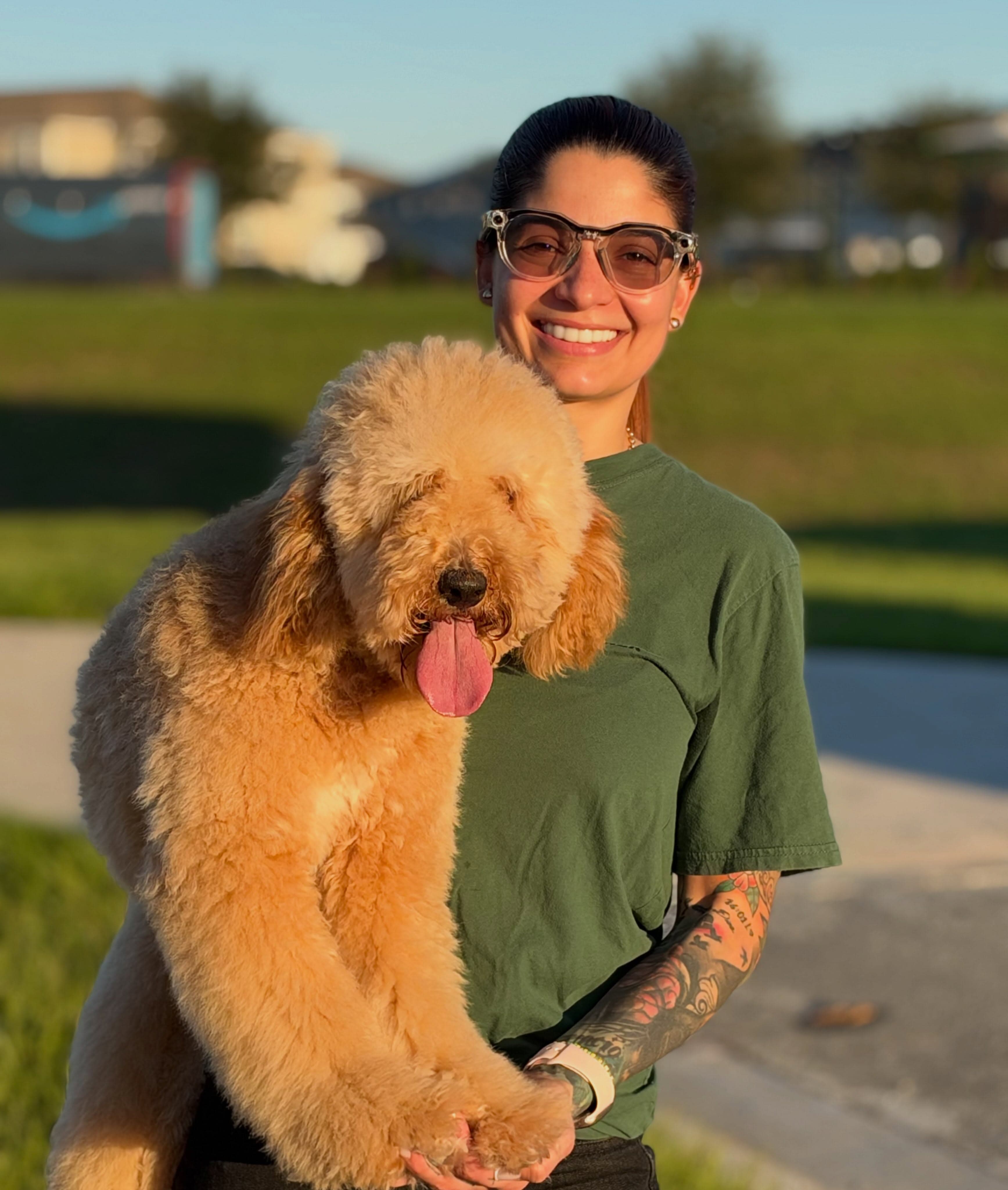 Trainer smiling with Arya, a cream-colored poodle